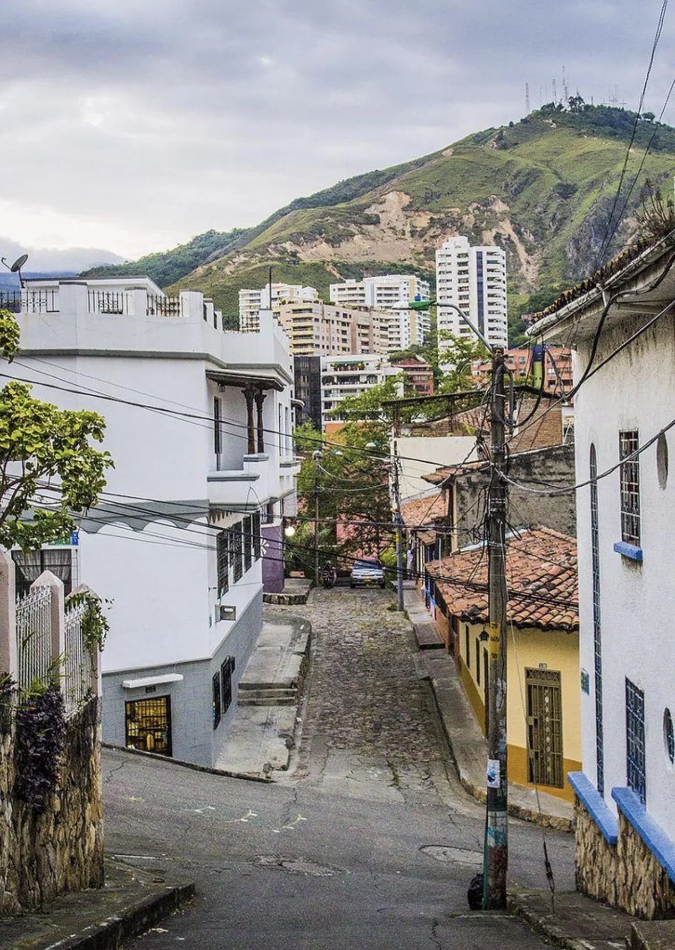 Hillside neighborhood in Cali, Colombia with white homes and green mountain backdrop
